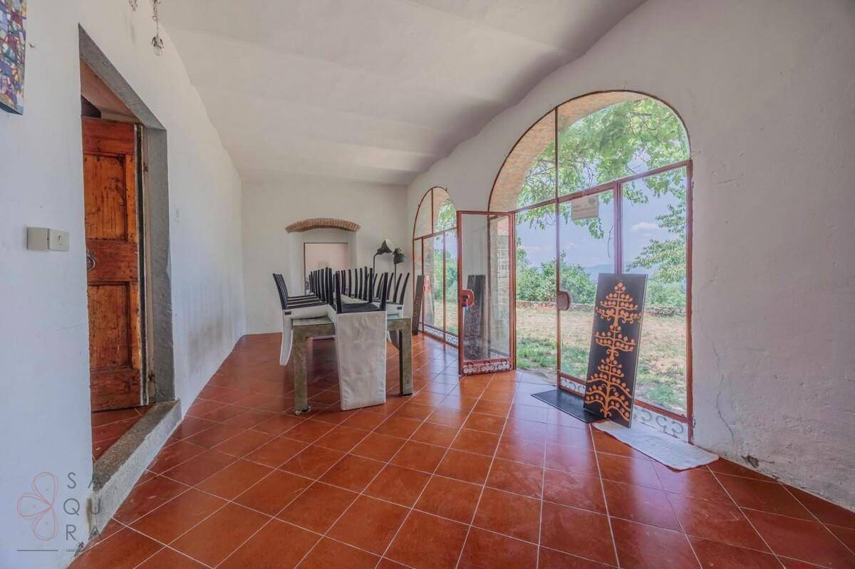 Helles Esszimmer mit großen Bogenfenstern, die einen weiten Blick in die Landschaft bieten.