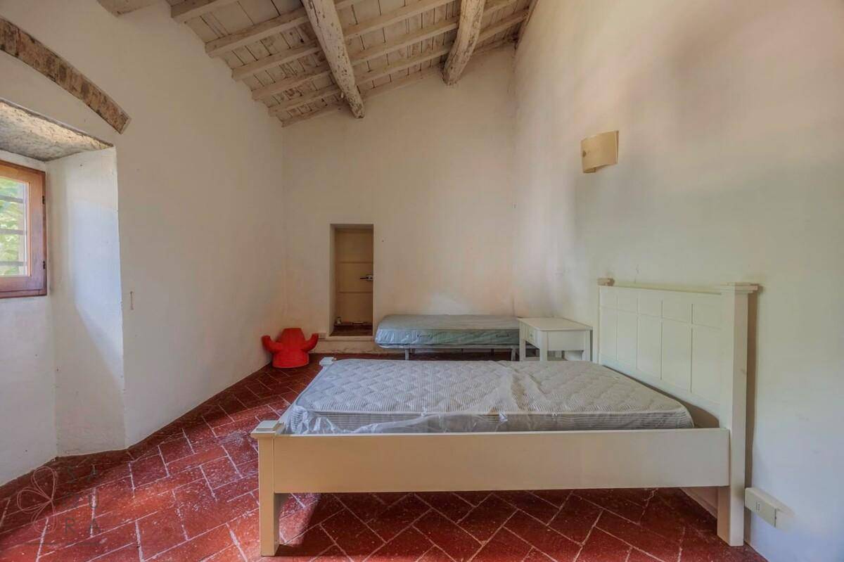 Schlafzimmer mit schrägen Decken, freiliegenden Holzbalken und Terrakottaboden.