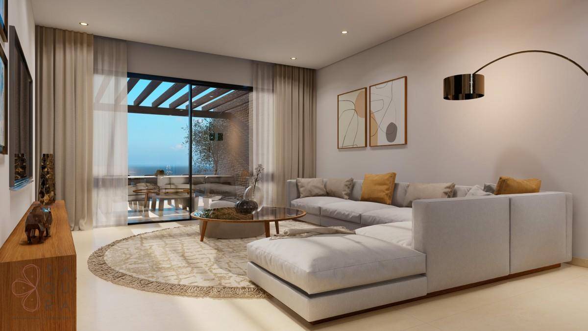 Helles Wohnzimmer mit modernem Sofa, Teppich und Zugang zur Terrasse mit Meerblick.