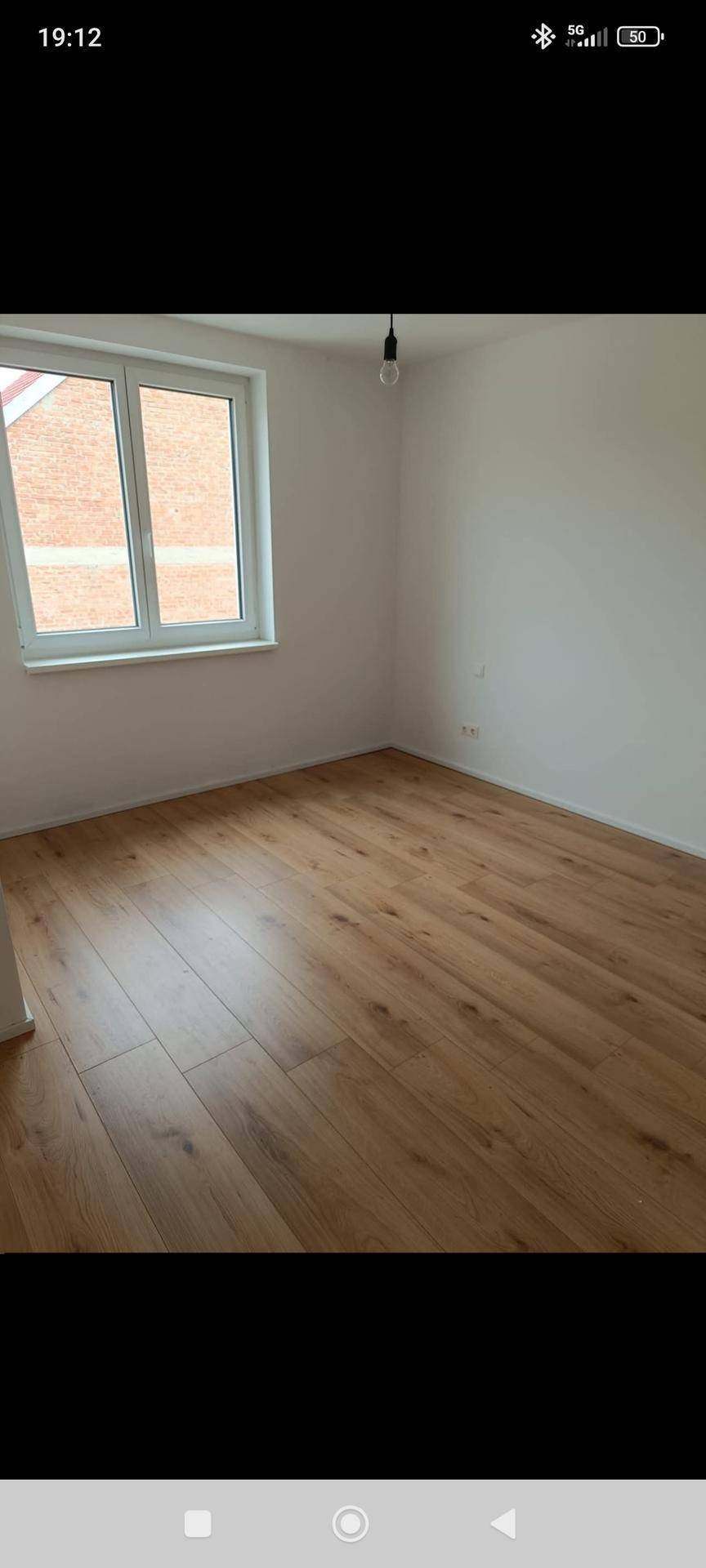 Helles Schlafzimmer mit Holzboden und Fenster, bereit zur individuellen Gestaltung.