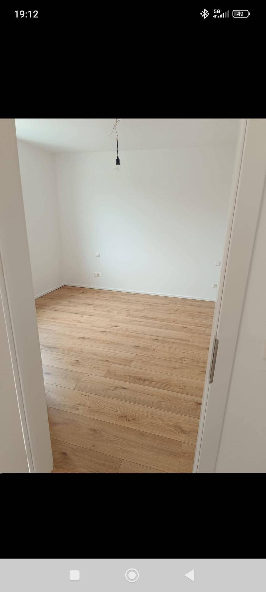 Leeres Zimmer mit hellem Holzboden und weißen Wänden, ideal für Schlaf- oder Arbeitsbereich.