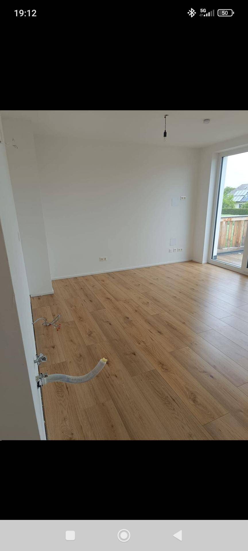 Geräumiges, helles Zimmer mit Holzboden und Balkonzugang, bereit für die Einrichtung.