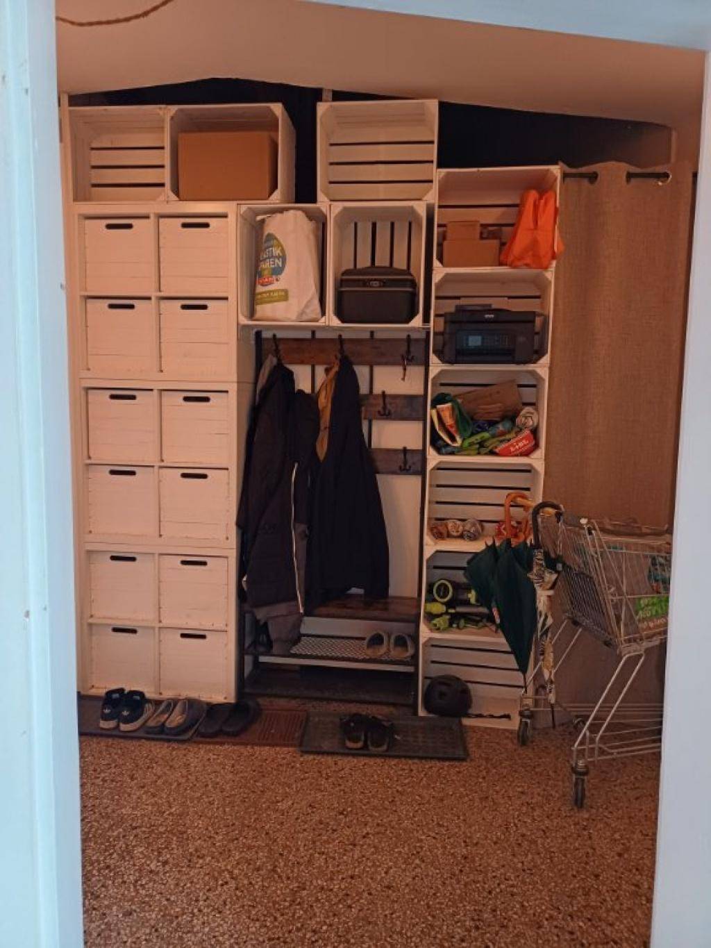 Eingangsbereich mit kreativer Aufbewahrung aus Holzkisten, Garderobe und Schuhablage.