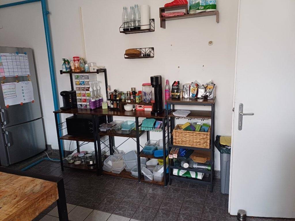Funktionale Küche mit offenem Regal, Mikrowelle und Kühlschrank auf Fliesenboden.