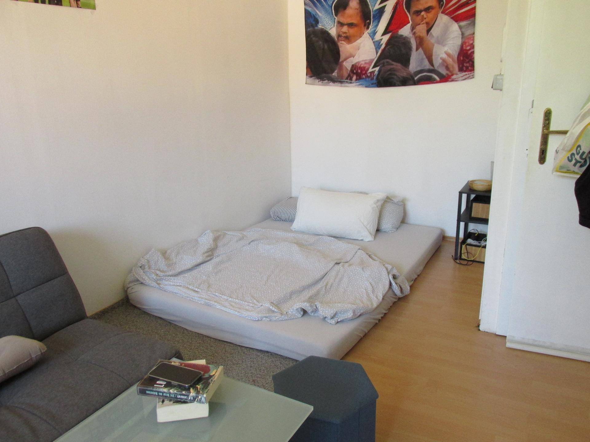 Schlafbereich mit Matratze auf dem Boden und Schlafsofa, ergänzt durch Wanddekoration.