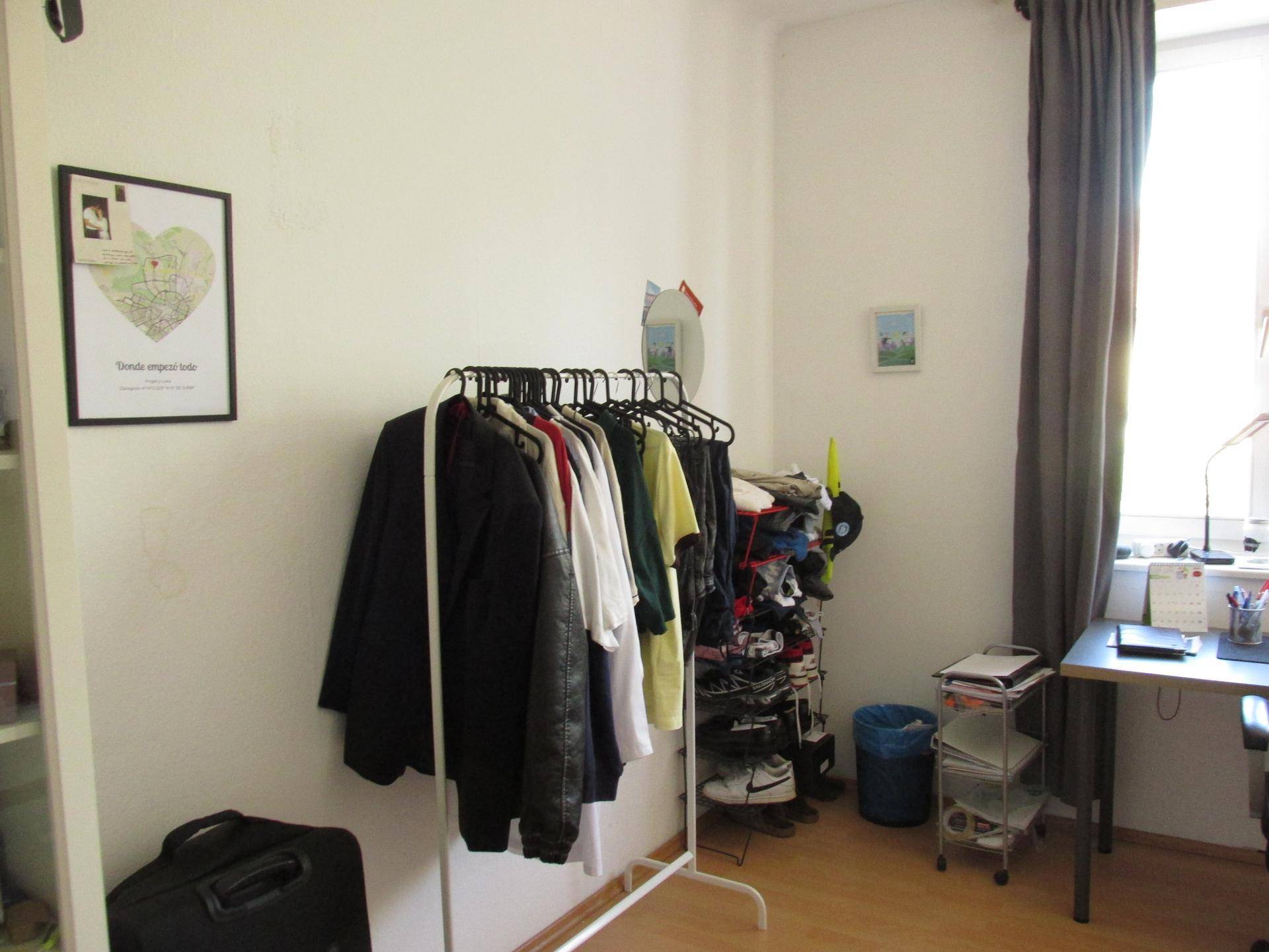 Kleiderstange und Schuhregal bieten Stauraum im hellen Wohn- und Schlafzimmer.
