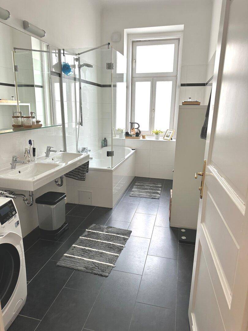 Modernes Badezimmer mit Badewanne, Dusche, Doppelwaschbecken und Fenster.
