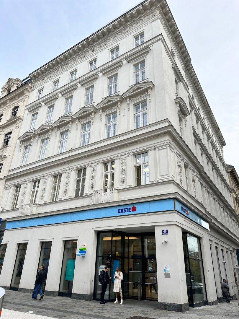 Historisches Gebäude mit klassischer Fassade und Geschäftsräumen im Erdgeschoss.