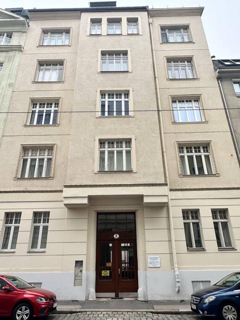 Klassische Fassade eines Mehrfamilienhauses mit vielen Fenstern und Holztür.