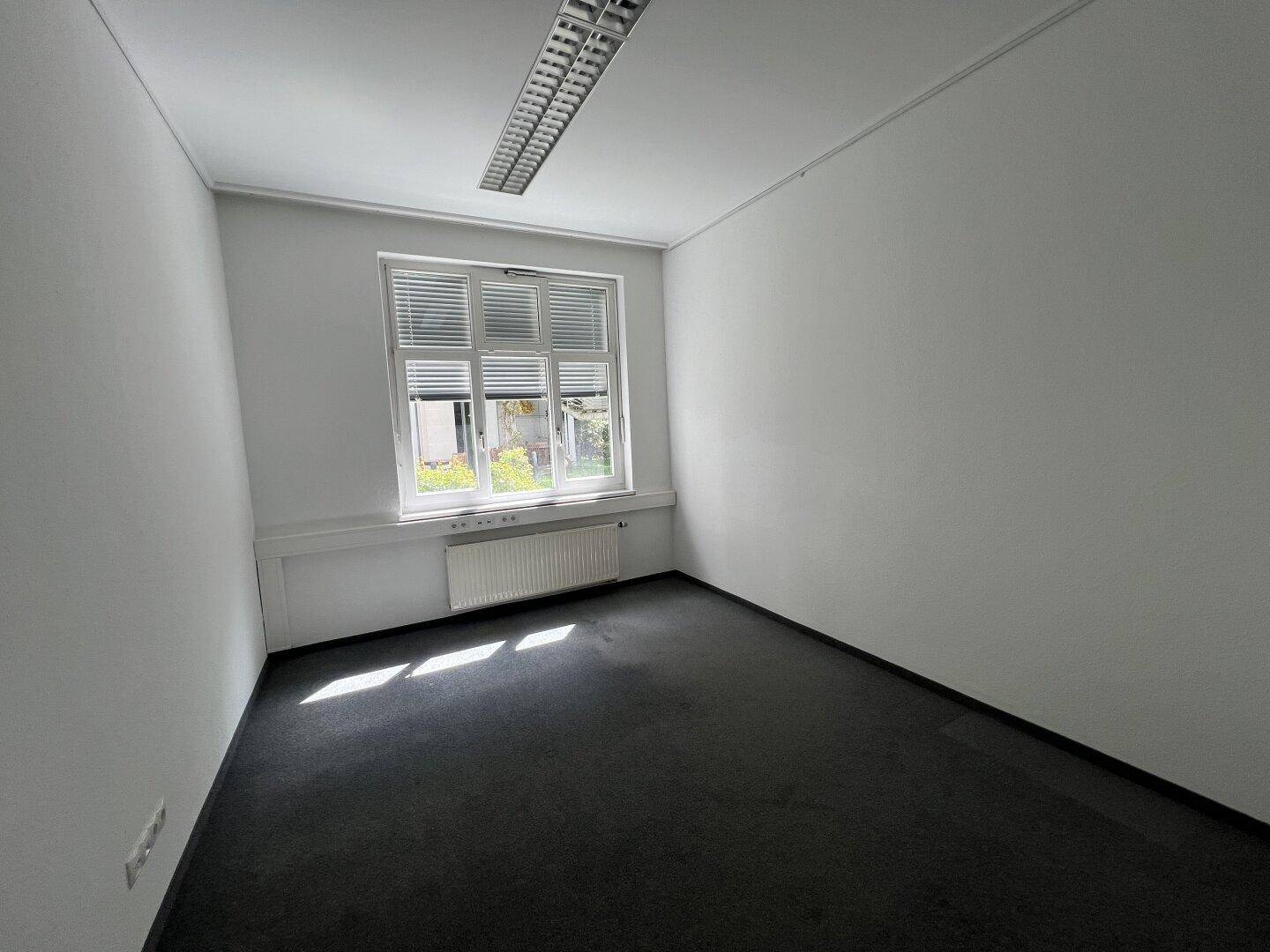 Kleines Büro mit Teppichboden und einem Fenster mit Jalousien, bietet Privatsphäre.