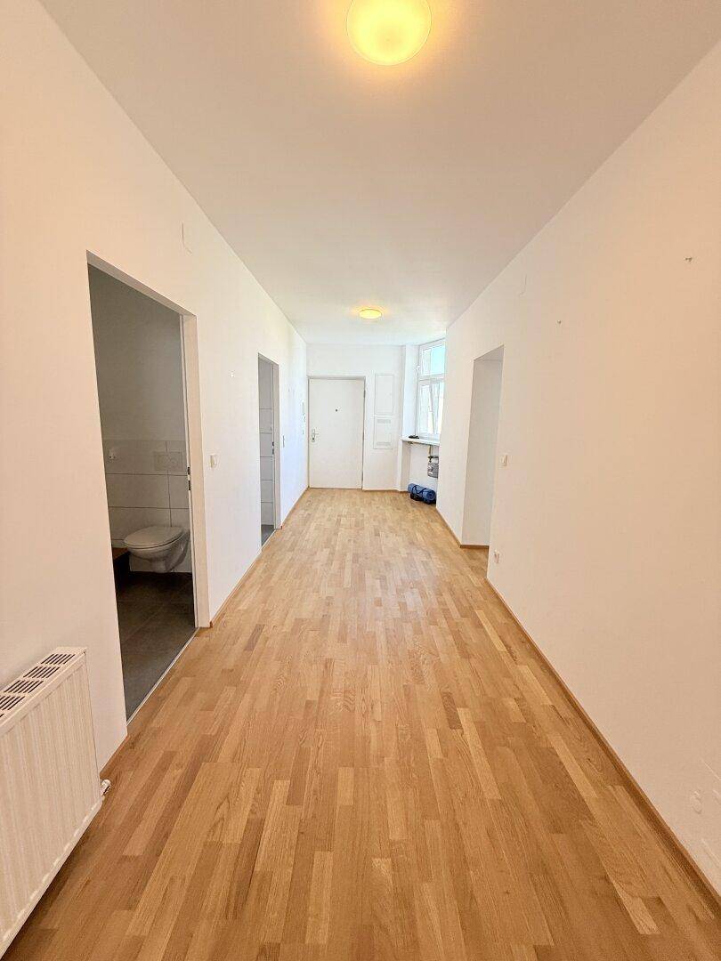 Langer Flur mit Parkettboden und Zugang zu verschiedenen Räumen, inklusive Gäste-WC.