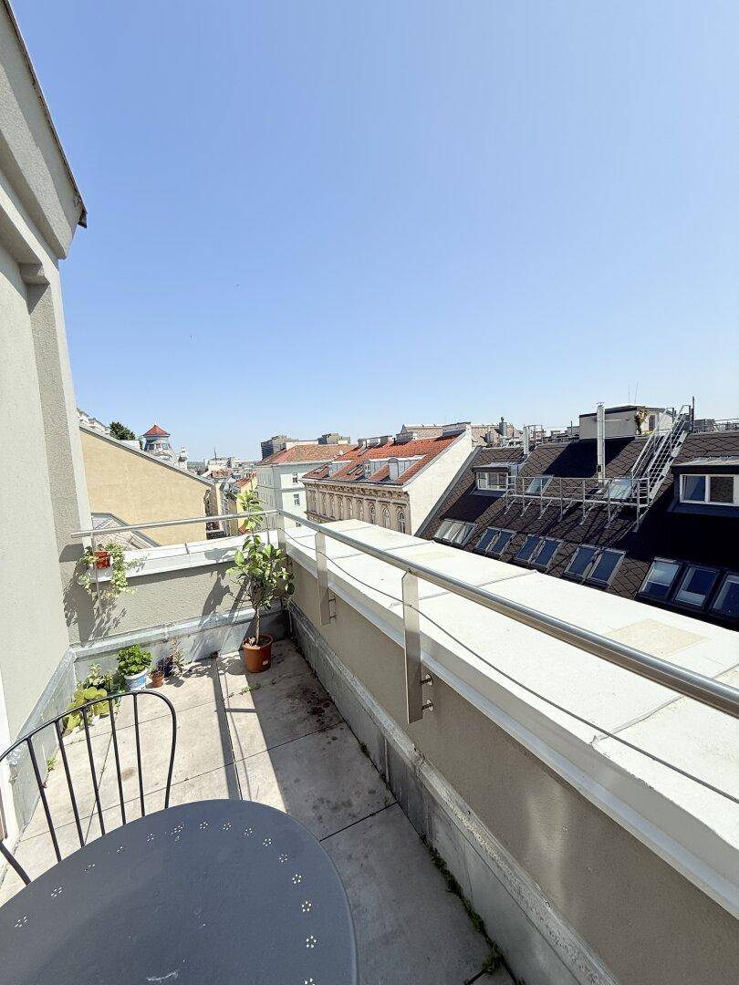 Sonniger Balkon mit Stadtblick und kleinem Tisch, ideal zum Entspannen im Freien.