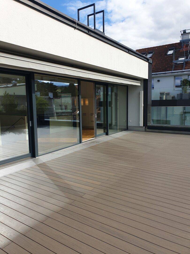 Weitläufige Dachterrasse mit Holzboden und Markise, bietet viel Platz für Outdoor-Aktivitäten.