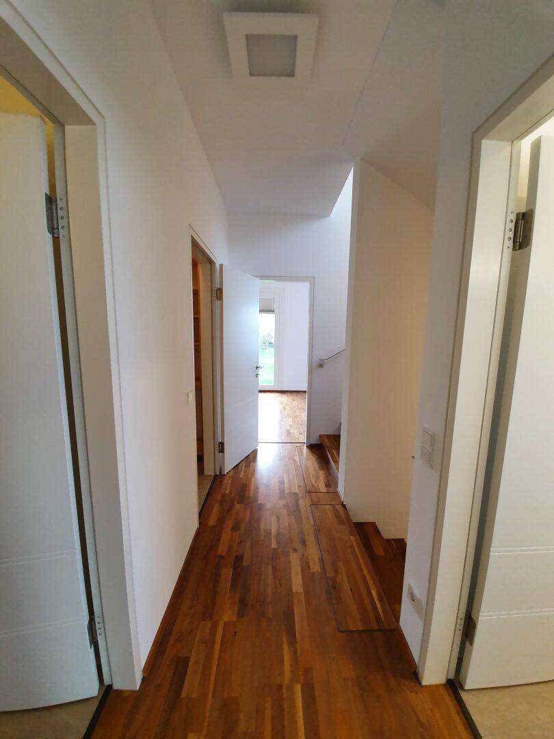 Heller Flur mit Holzboden und mehreren Türen, verbindet verschiedene Räume der Wohnung.