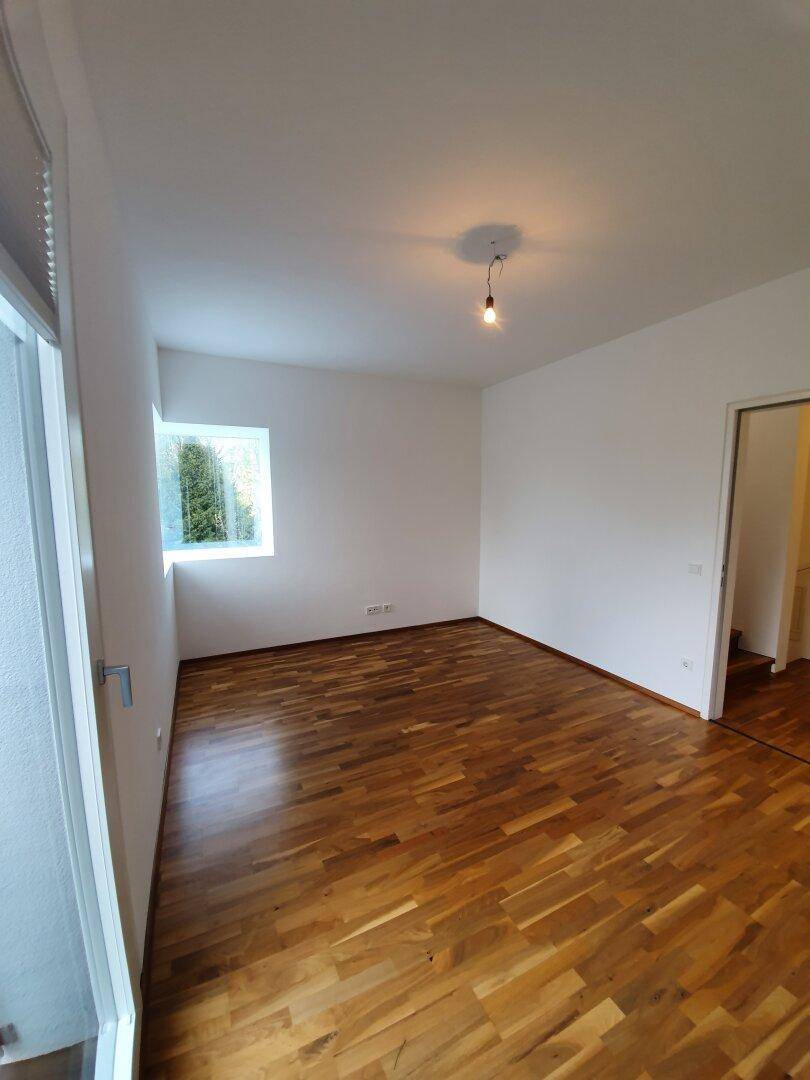 Unmöbliertes Schlafzimmer mit Holzboden und Fenster, bietet viel natürliches Licht.
