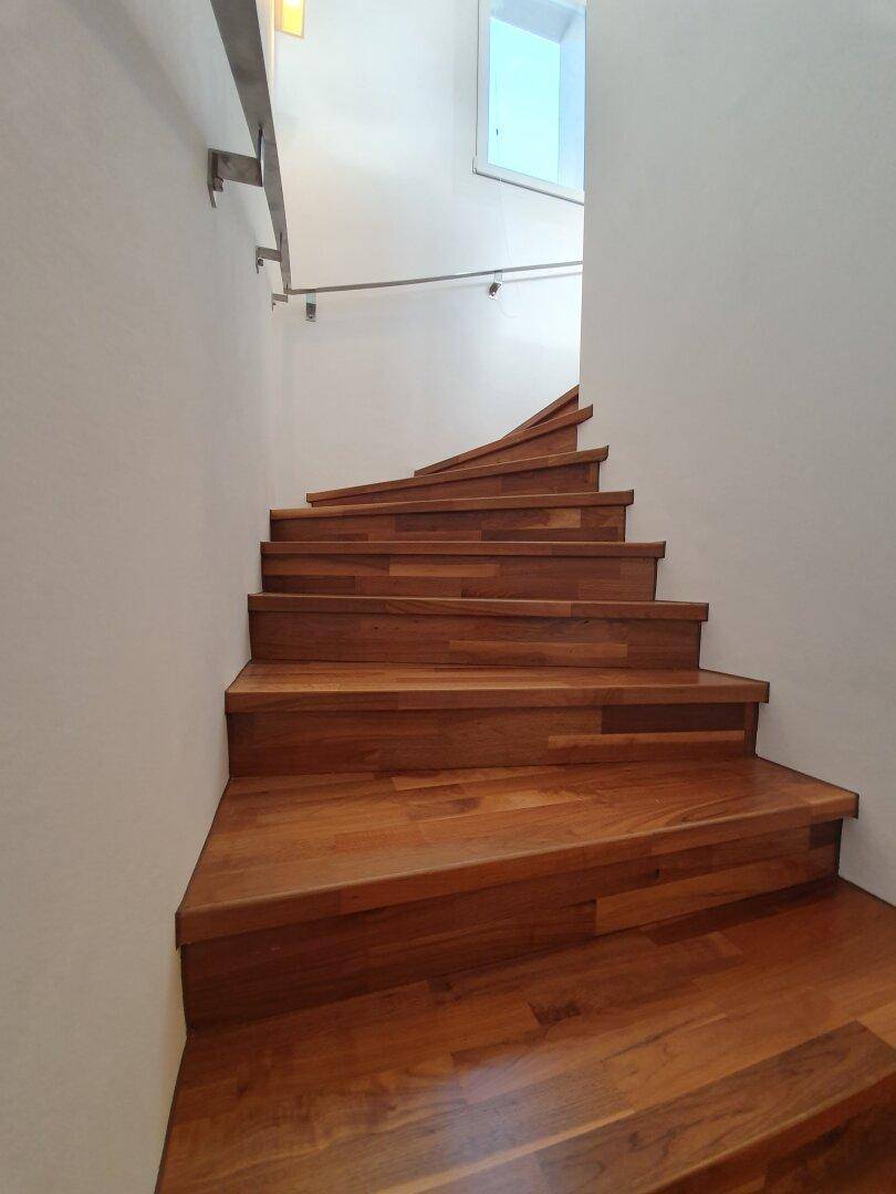 Elegante Holztreppe mit geschwungenen Stufen und schlichtem Geländer, führt in die nächste Etage.
