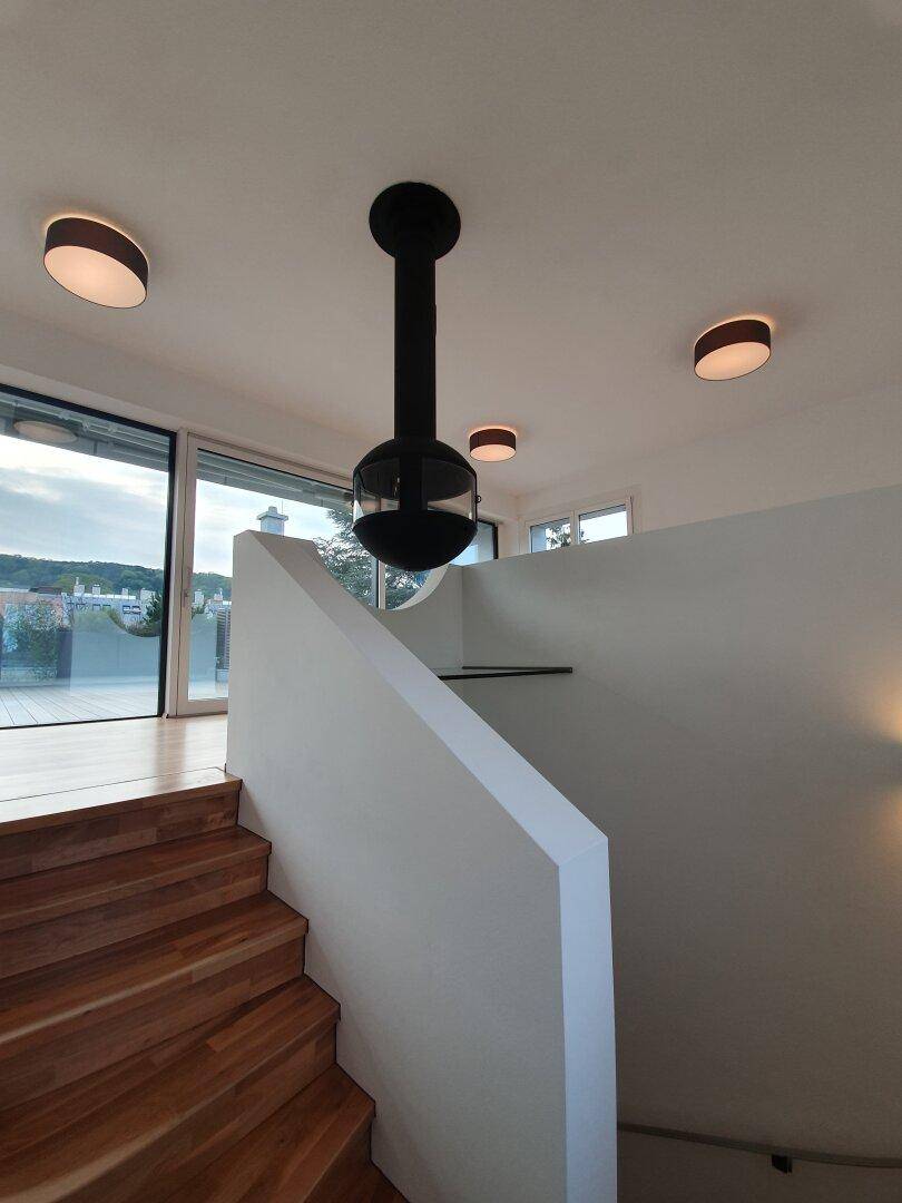Elegante Holztreppe mit modernem Hängekamin, führt zu den oberen Etagen des Hauses.