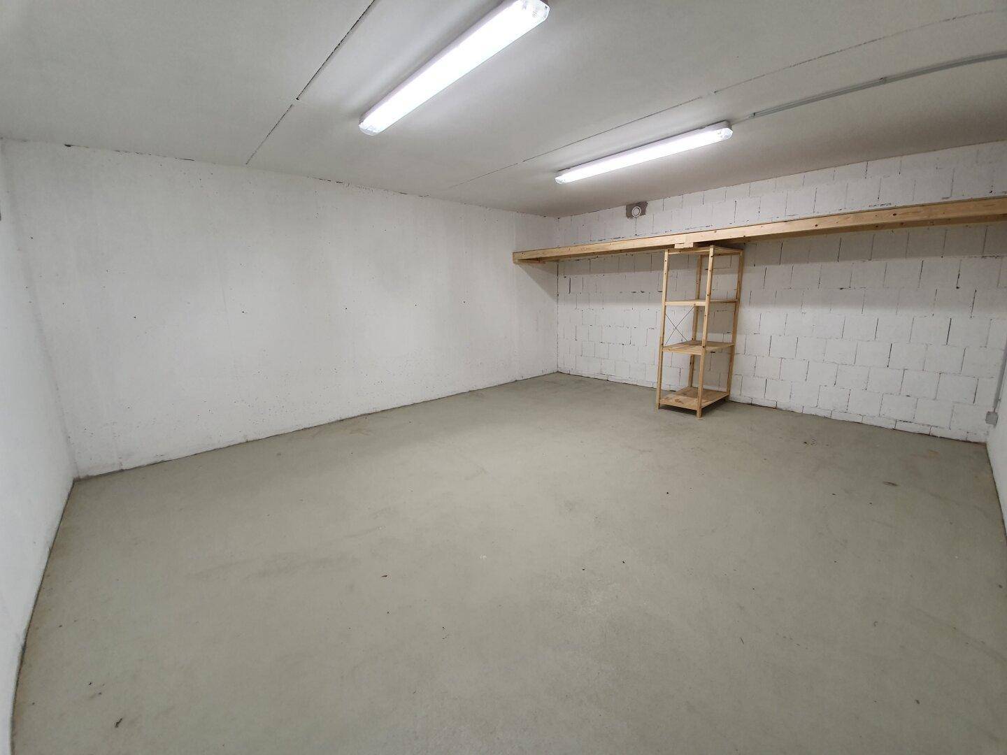 Geräumiger Abstellraum im Keller mit Betonboden und einfachen Holzregalen.