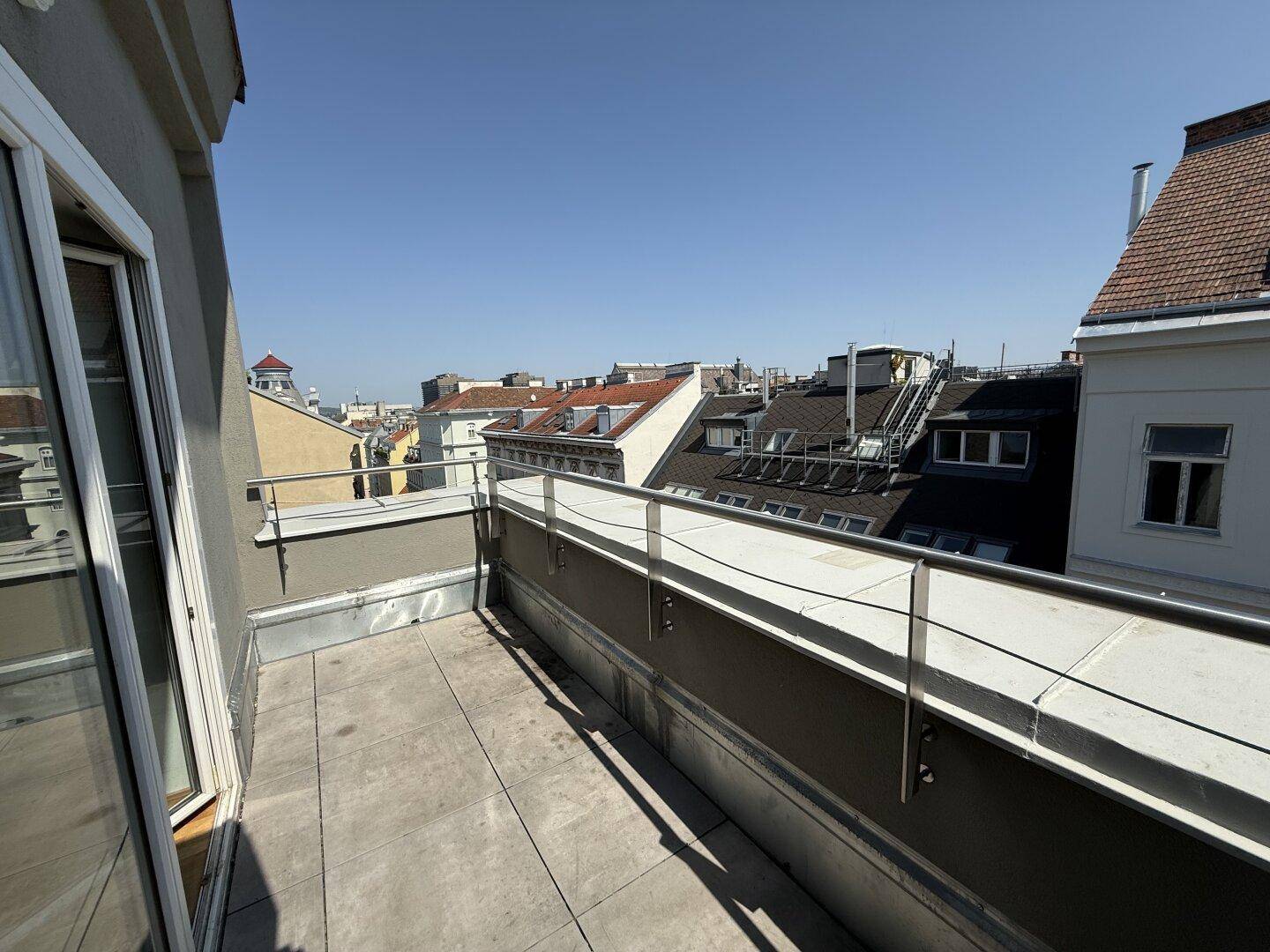 Großer Balkon mit weitem Stadtblick und Schiebetür, ideal für sonnige Tage.