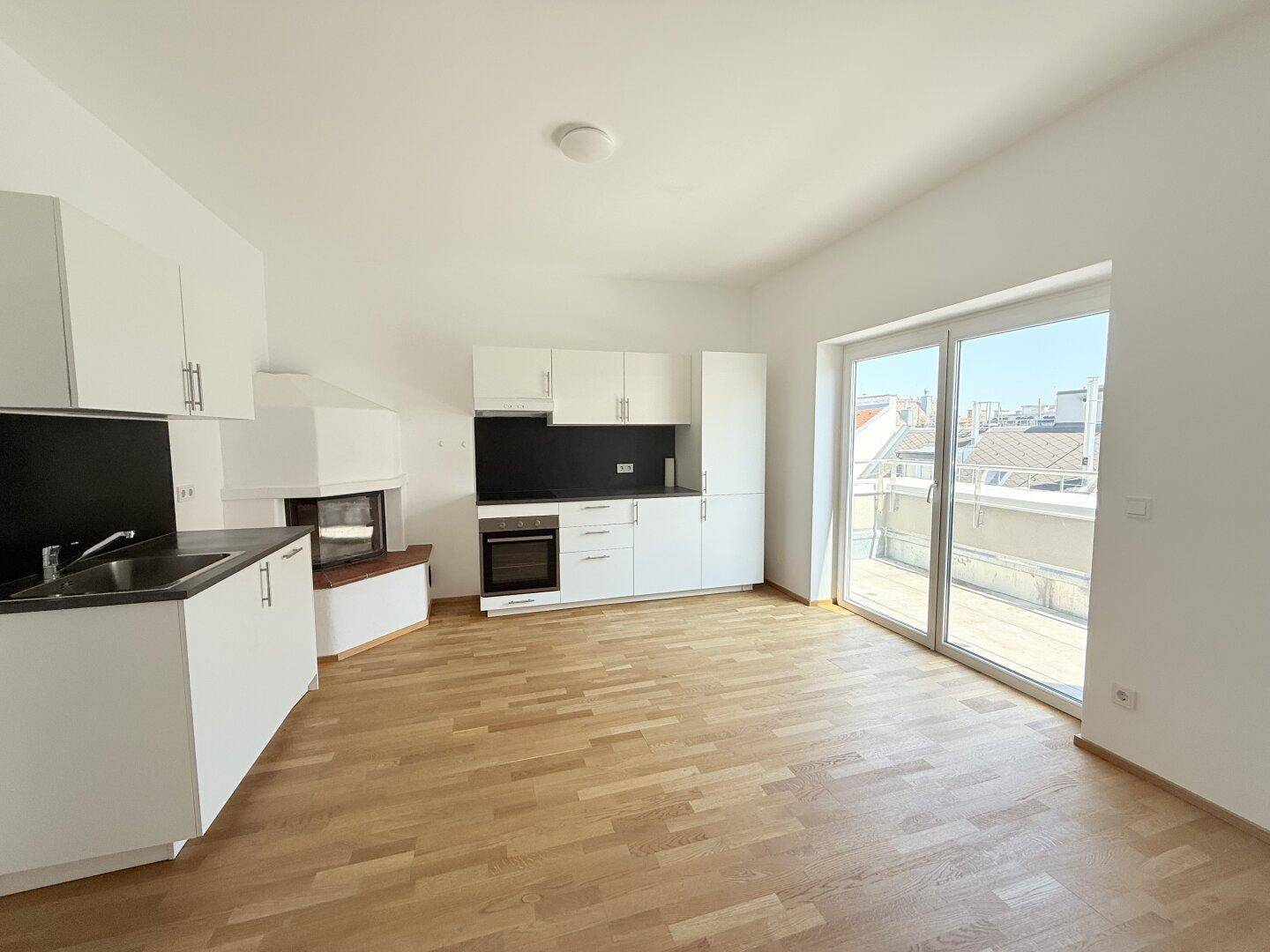 Offener Wohn- und Essbereich mit moderner Küche, Kamin und Zugang zur Terrasse.