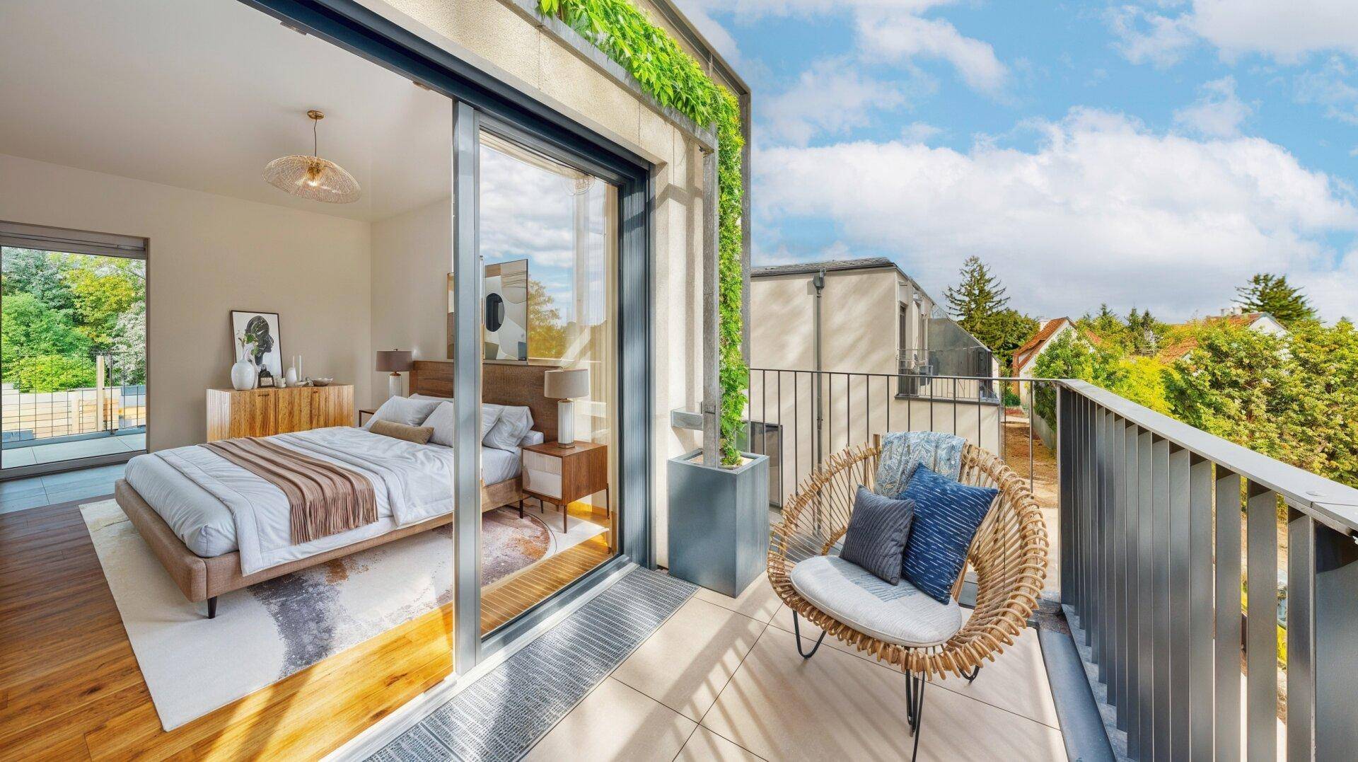Helles Schlafzimmer mit Zugang zu einem Balkon, ausgestattet mit einem Korbsessel.