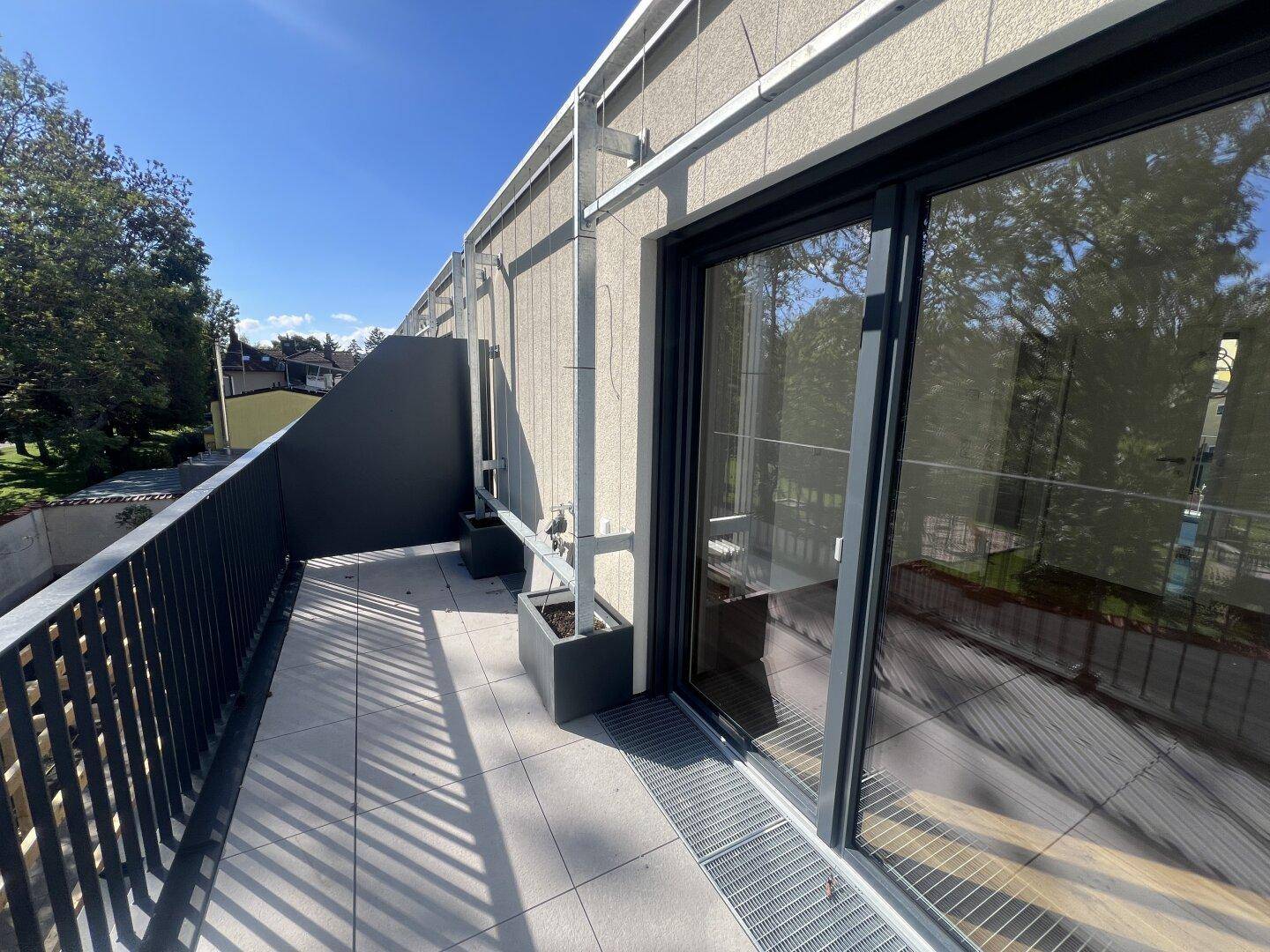 Geräumiger Balkon mit Fliesenboden und modernem Metallgeländer, ideal für Entspannung.