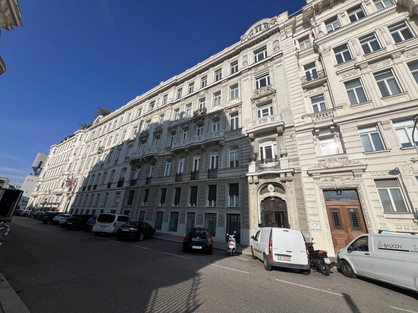 Prächtige historische Fassade eines Altbaus mit vielen Fenstern und Balkonen unter blauem Himmel.