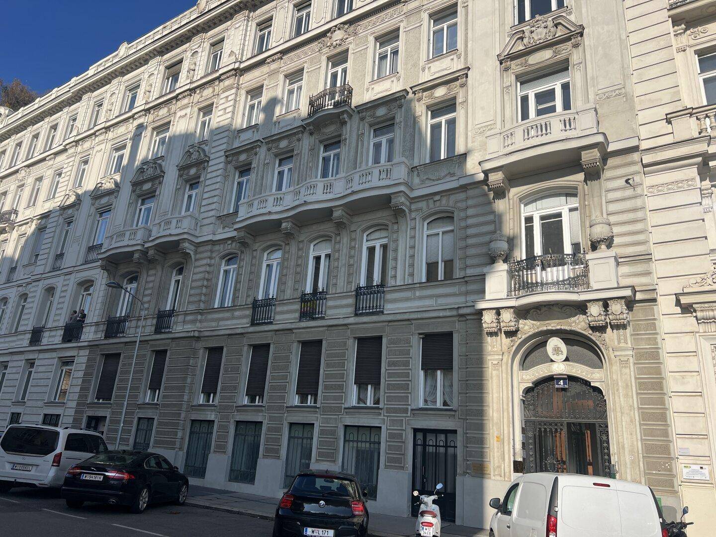 Prächtige historische Fassade eines Altbaus mit vielen Fenstern und Balkonen unter blauem Himmel.