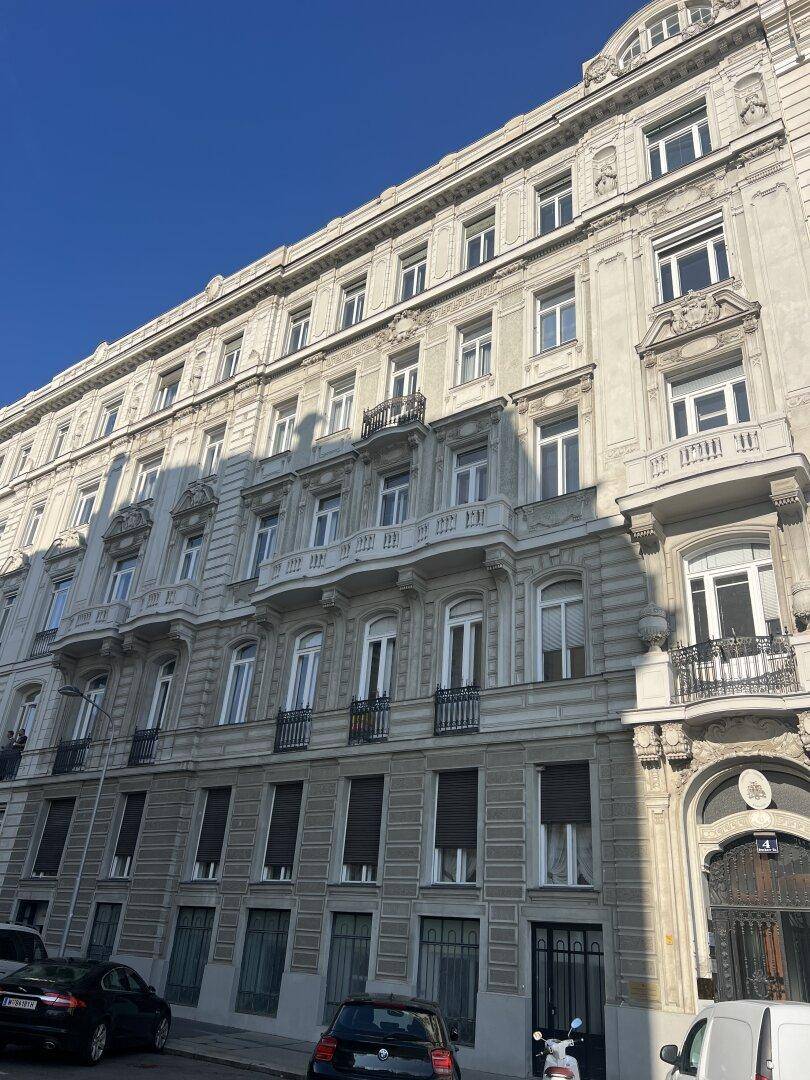 Prächtige historische Fassade eines Altbaus mit vielen Fenstern und Balkonen unter blauem Himmel.