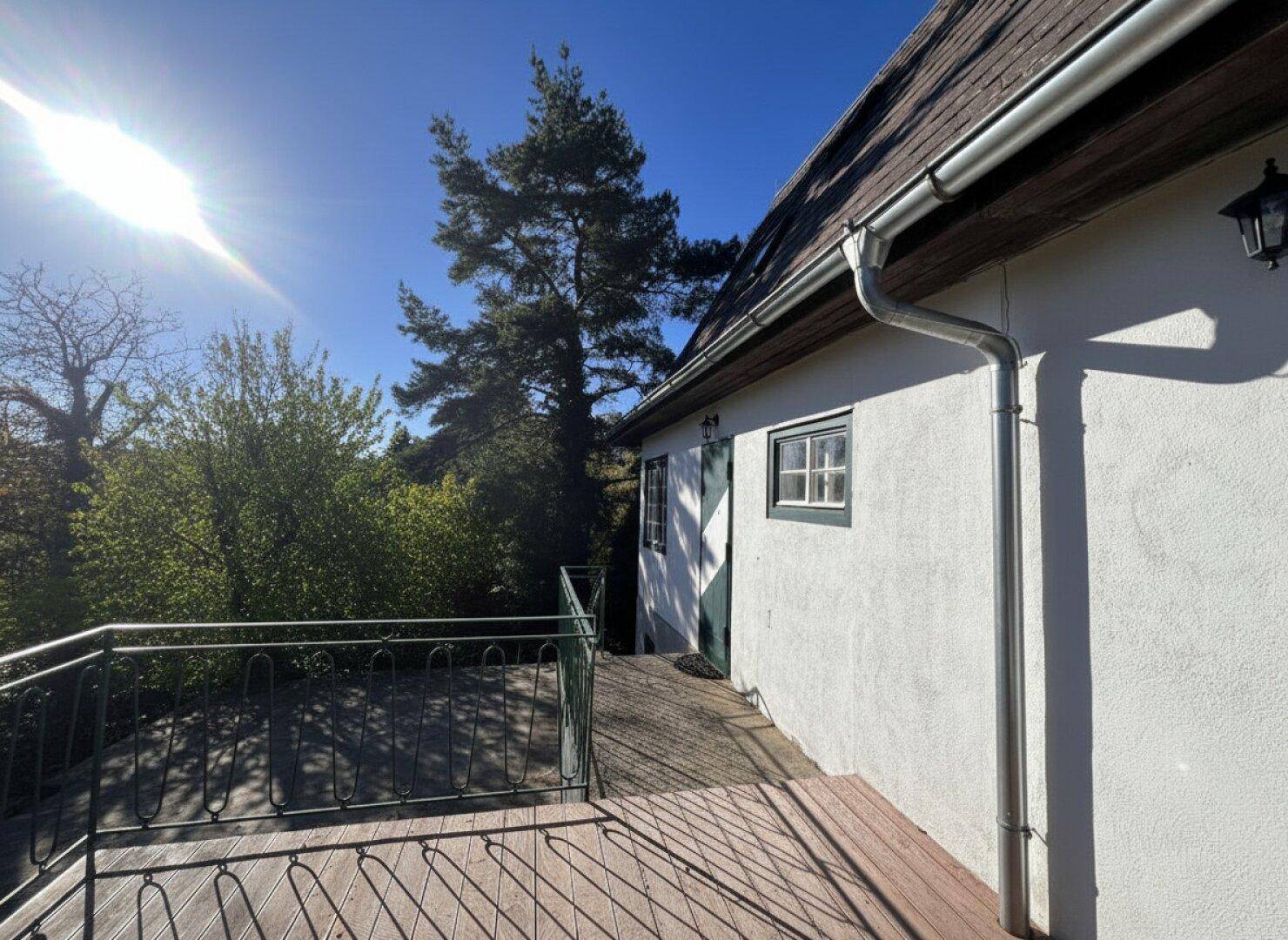 Seitliche Terrasse mit Sonnenschirm und Sitzgelegenheiten, angrenzend an das Haus.