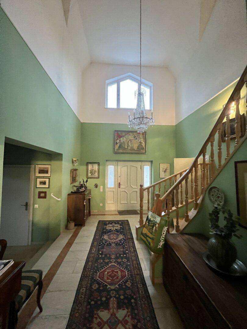 Heller Eingangsbereich mit hoher Decke, grünen Wänden und elegantem Kronleuchter.
