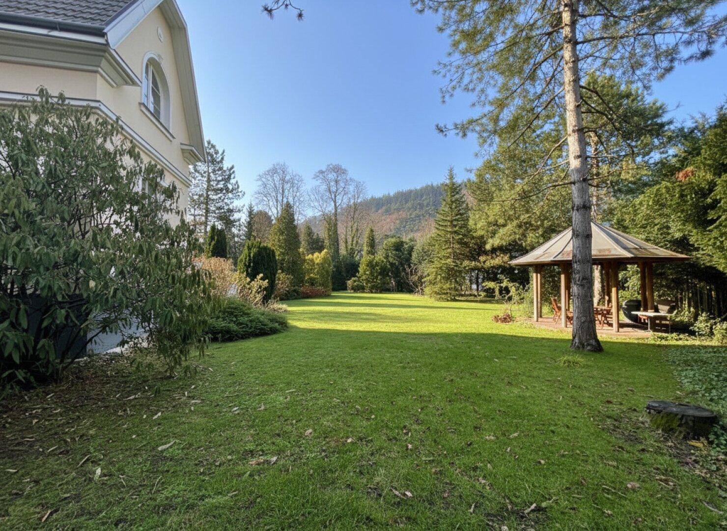 Großer Garten mit Rasenfläche, Gartenlaube und weitem Blick auf die umliegende Landschaft.