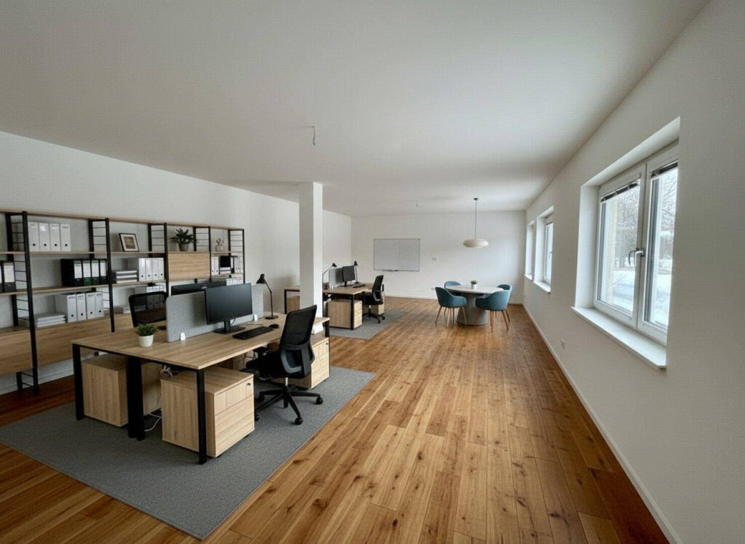 Geräumiges, modernes Büro mit Holzboden, mehreren Arbeitsplätzen und viel Tageslicht.