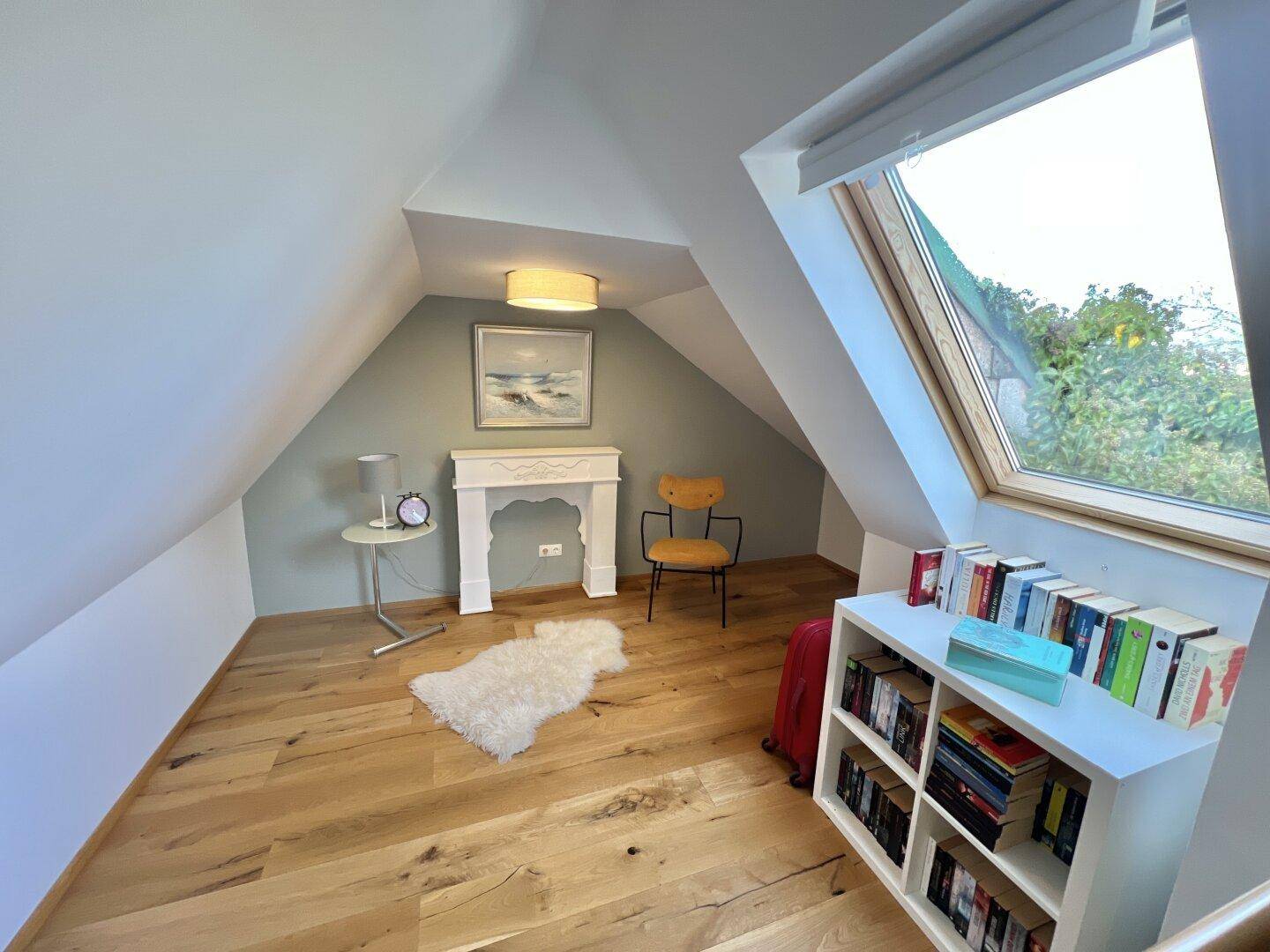 Helles Dachgeschosszimmer mit Holzboden und Dachfenster, ideal als Büro oder Leseecke.
