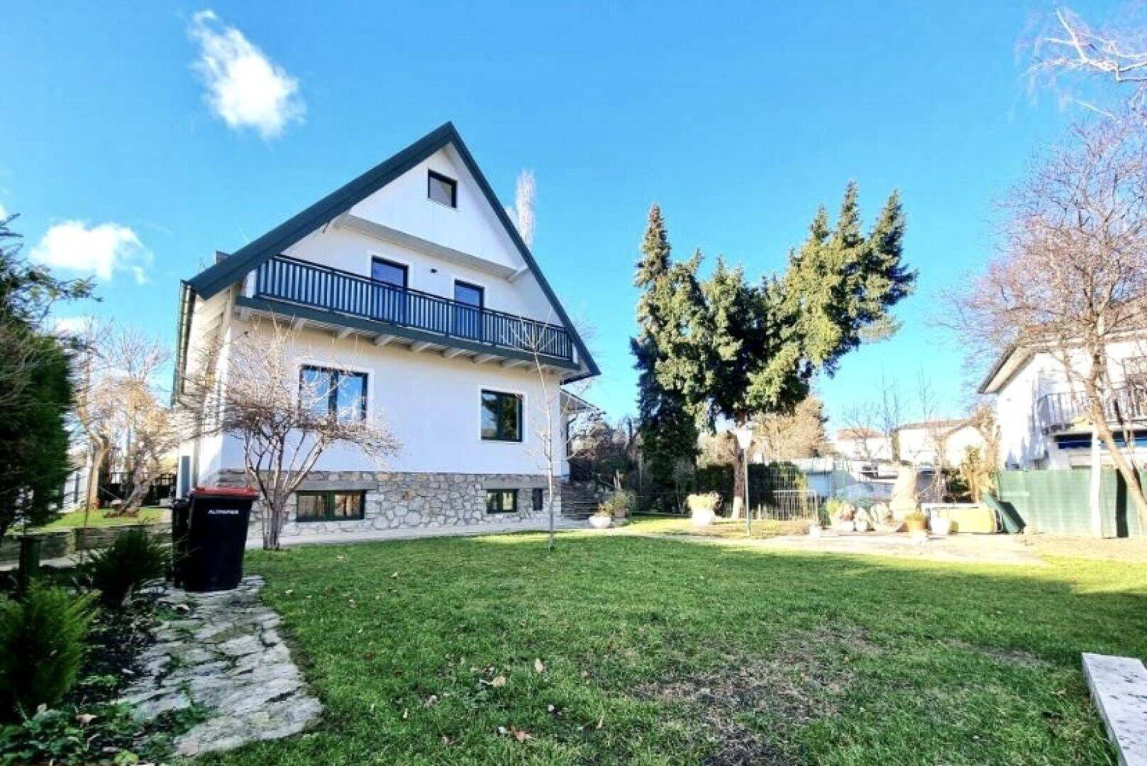 Einfamilienhaus mit großem, sonnigem Garten und gepflegter Rasenfläche.