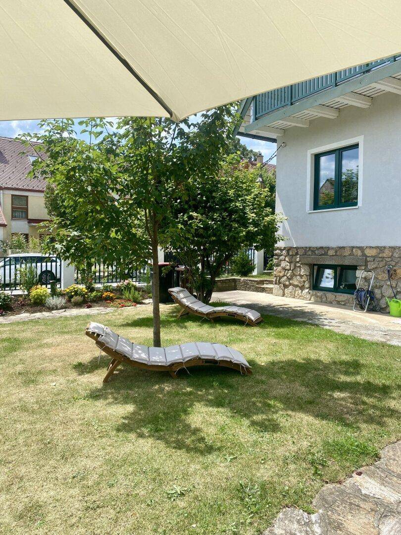 Sonnige Gartenecke mit Liegestühlen und Sonnenschirm, ideal zum Entspannen im Freien.