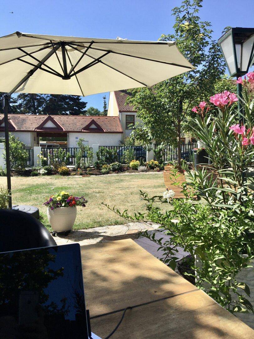 Gemütlicher Gartenbereich mit Sonnenschirm und Blick auf die grüne Umgebung.