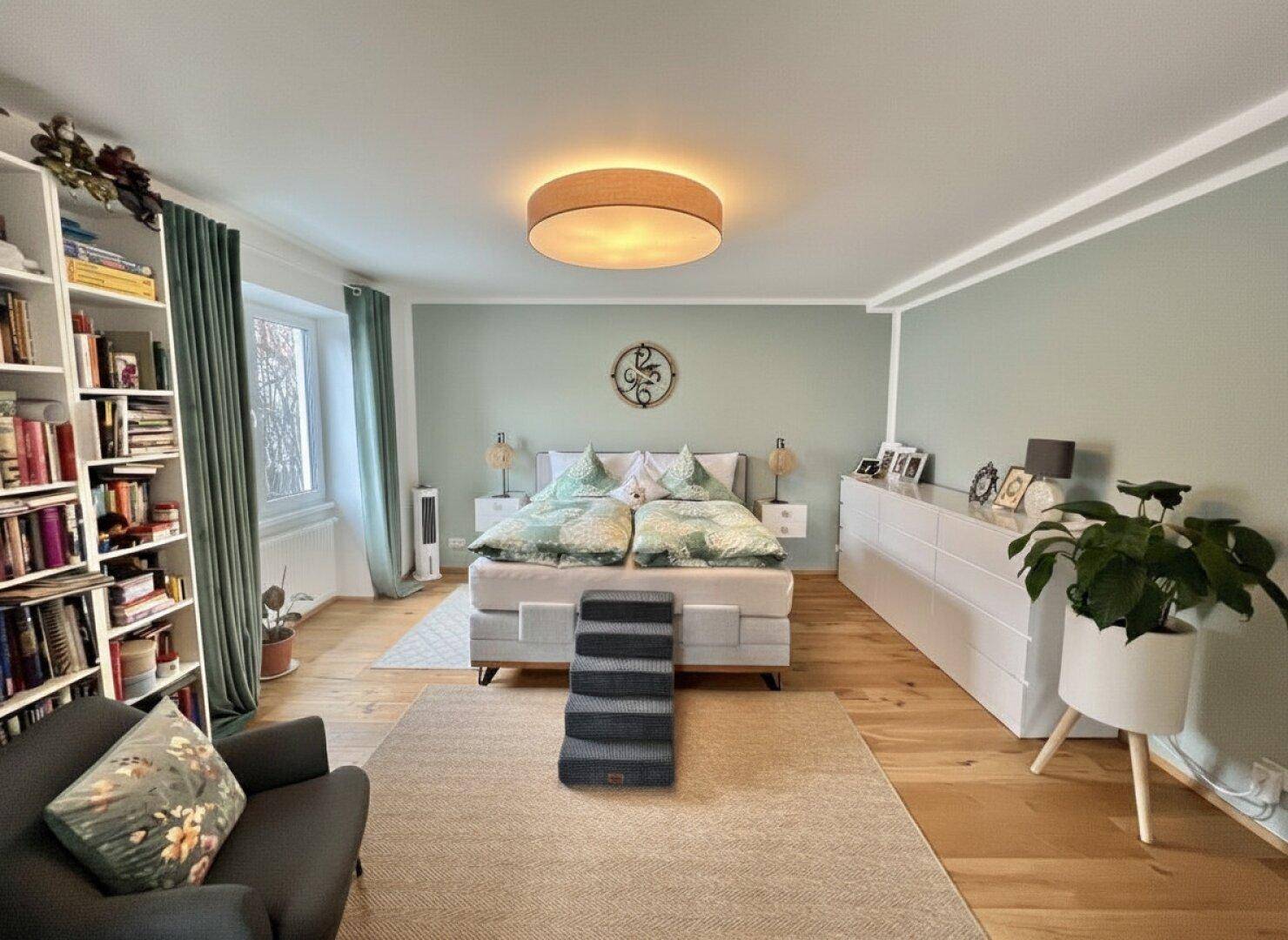 Geräumiges Schlafzimmer mit hellgrünen Wänden, Holzboden und großem Bett, gut beleuchtet.