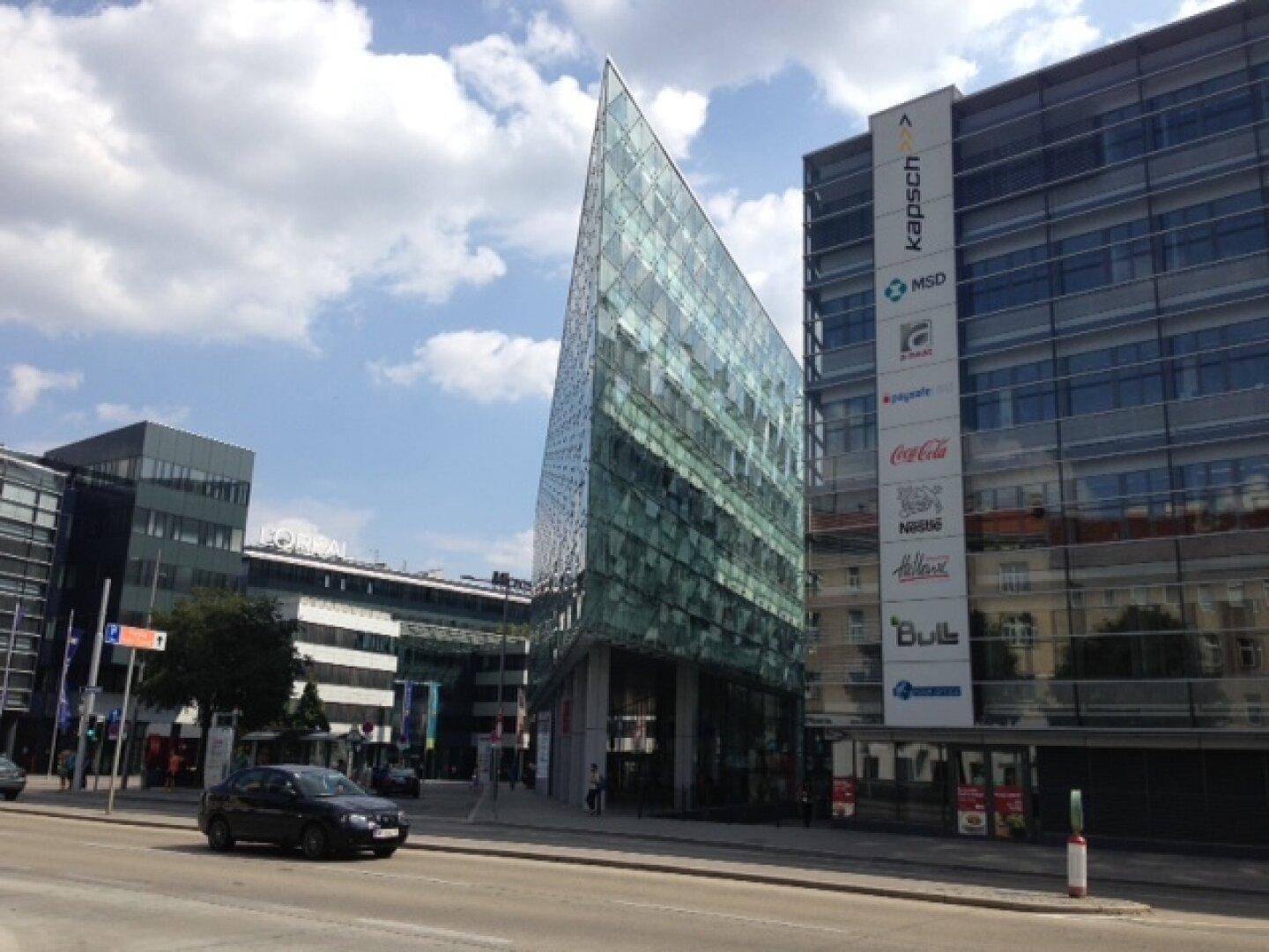Markantes Bürogebäude mit spitzer Glasfassade und modernen Elementen an einer belebten Straße.