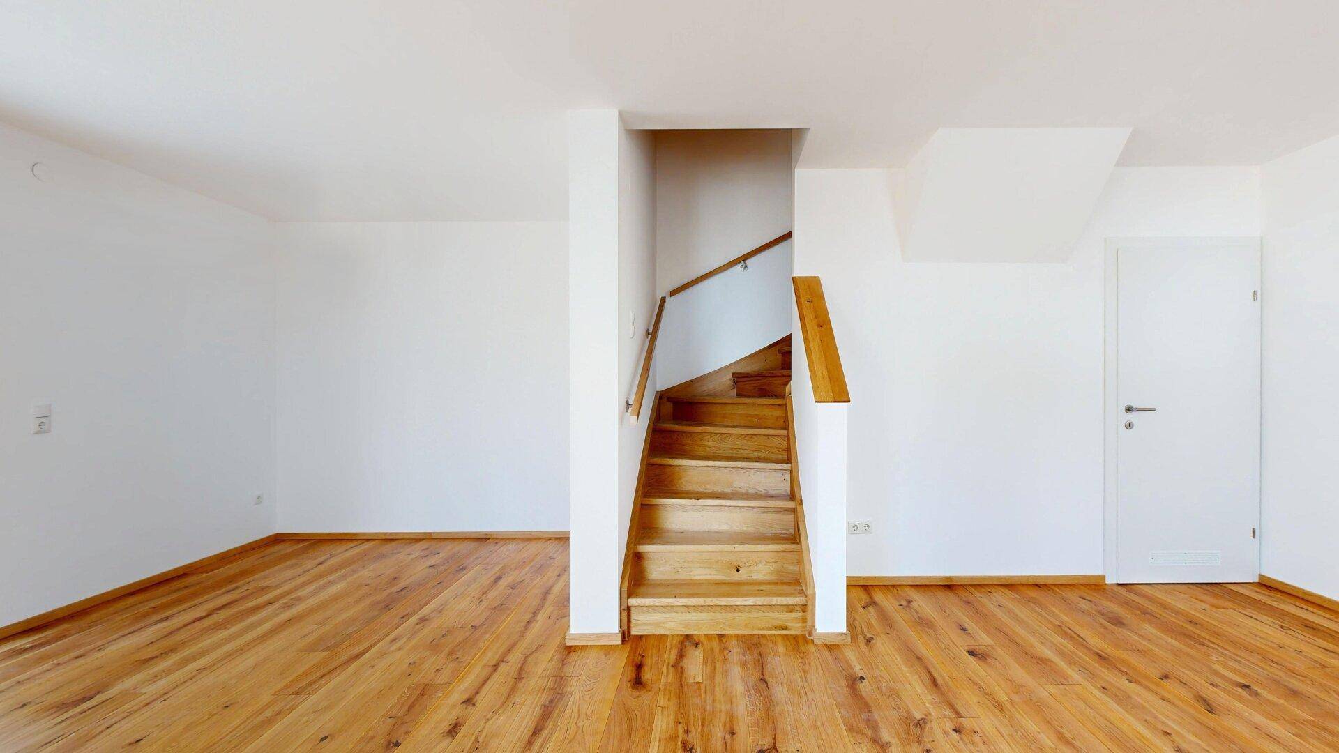 Heller Flur mit Holztreppe und Holzboden, der verschiedene Bereiche des Hauses verbindet.