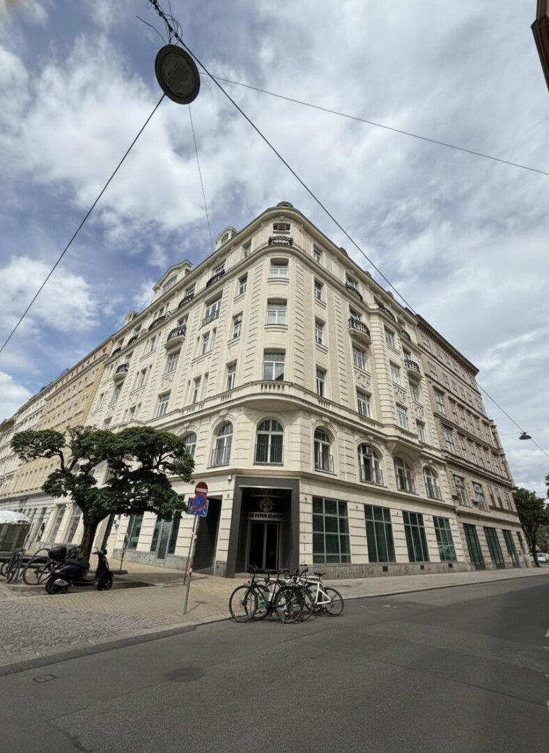 Historisches Eckgebäude mit klassischer Architektur und vielen Fenstern in urbaner Umgebung.