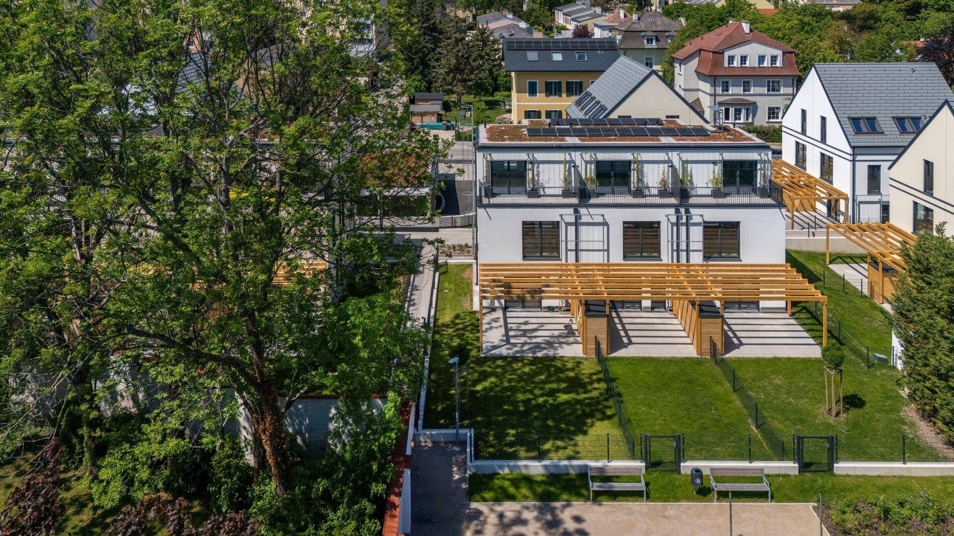Luftaufnahme einer modernen Wohnanlage mit Reihenhäusern, Gärten und Solaranlagen auf den Dächern.