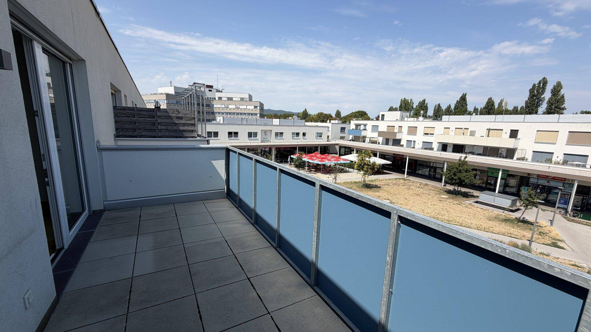 Weitläufige Terrasse mit Fliesenboden und Panoramablick auf die Wohnanlage und den Innenhof.
