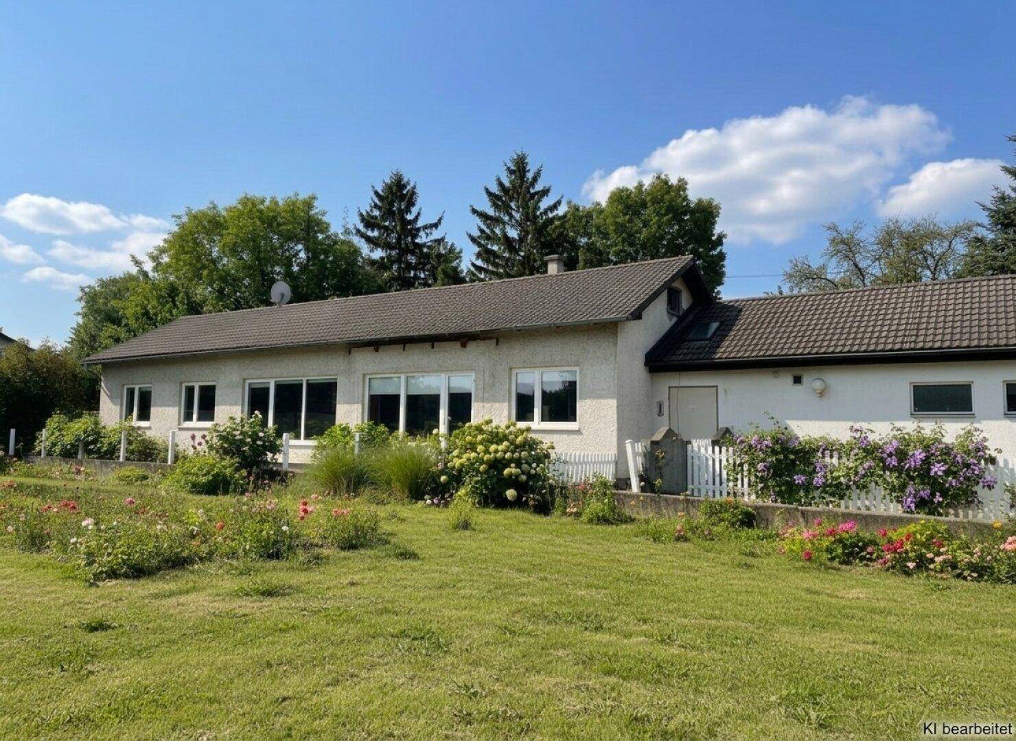 Ansicht des Gebäudes mit gepflegtem Vorgarten und blühenden Sträuchern an einem sonnigen Tag.