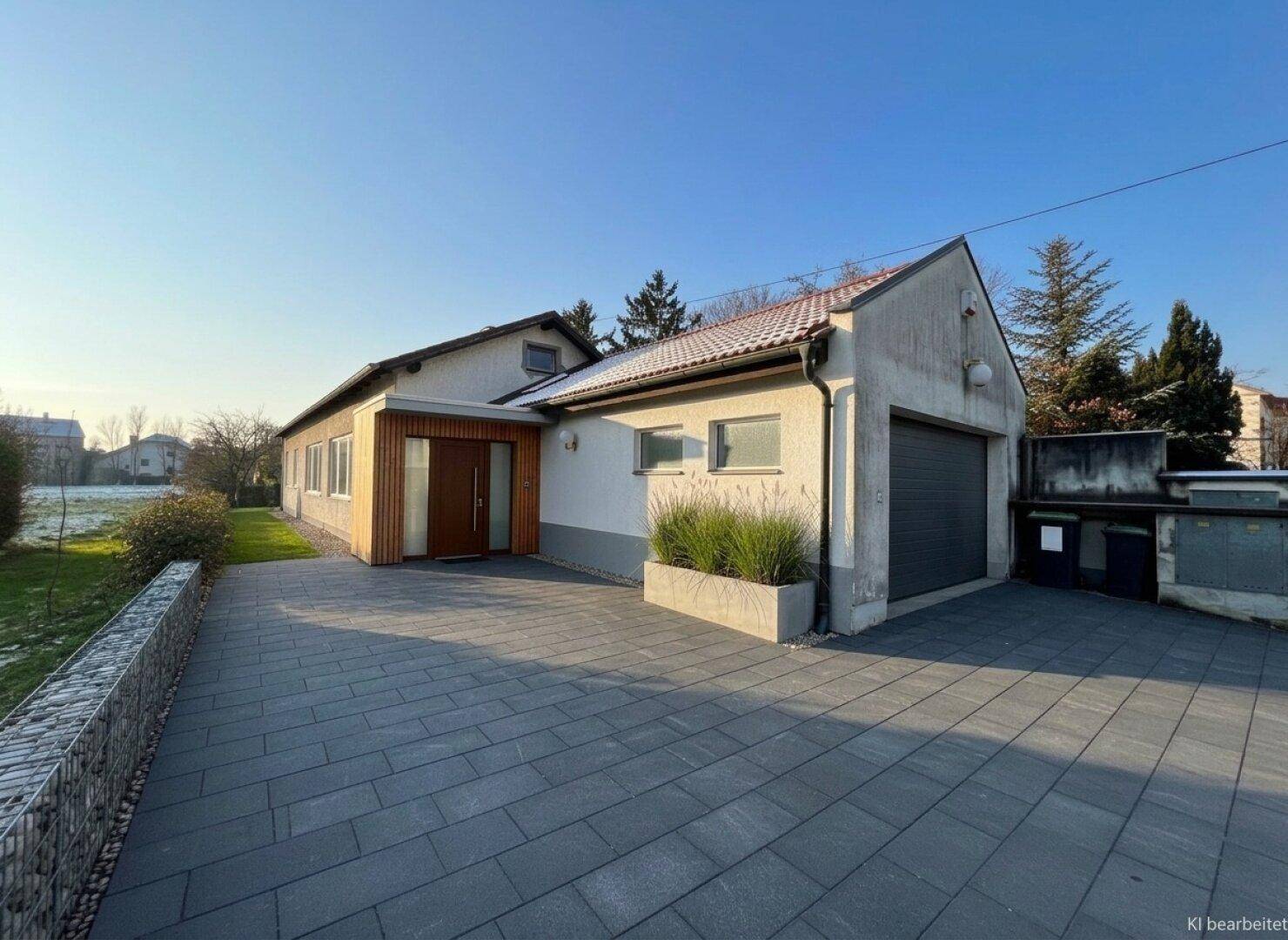Gebäudefassade mit modernem Eingangsbereich, gepflasterter Auffahrt und integrierter Garage.