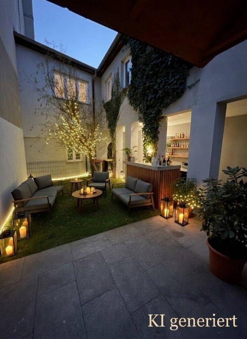 Stimmungsvoller Gartenbereich im Innenhof bei Nacht, beleuchtet mit Lichterketten und Laternen.