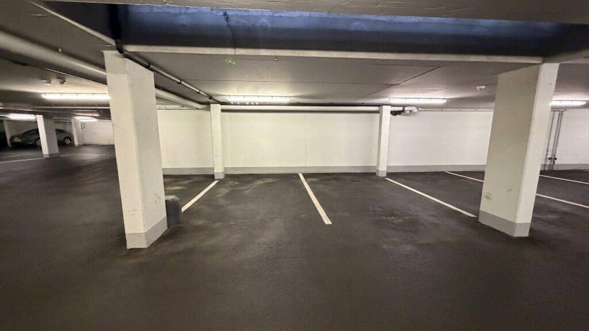 Geräumige Tiefgarage mit markierten Stellplätzen und sichtbaren Stützpfeilern.