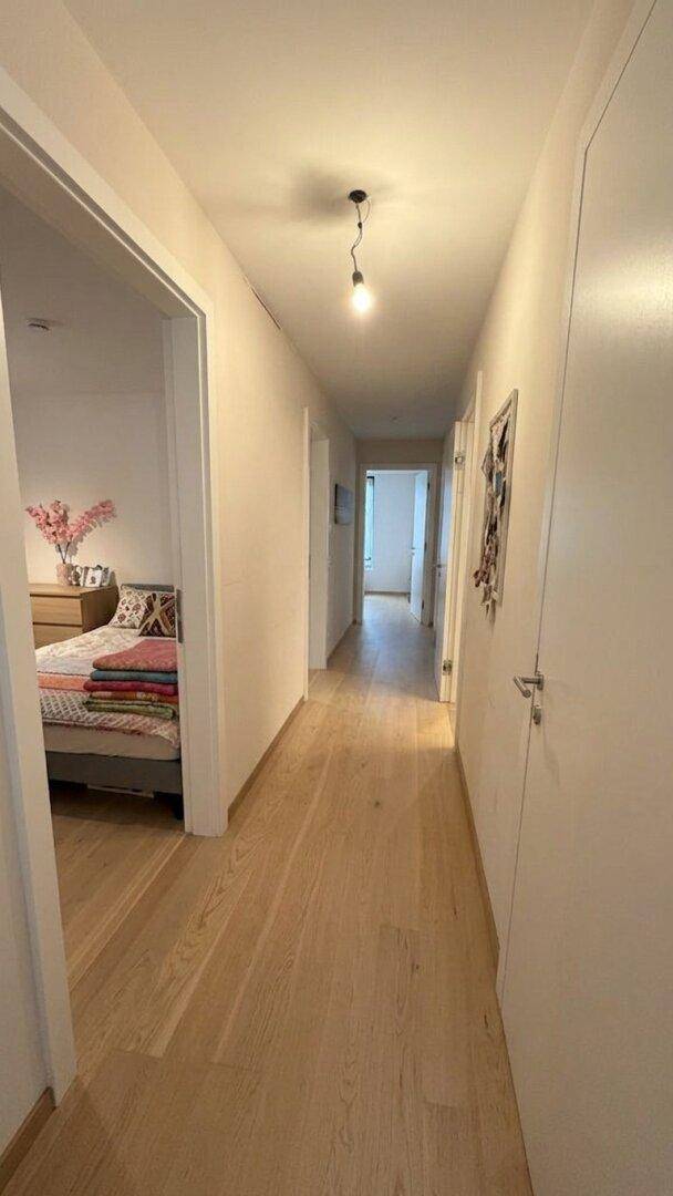 Langer, heller Flur mit Holzboden, der zu den verschiedenen Zimmern führt.