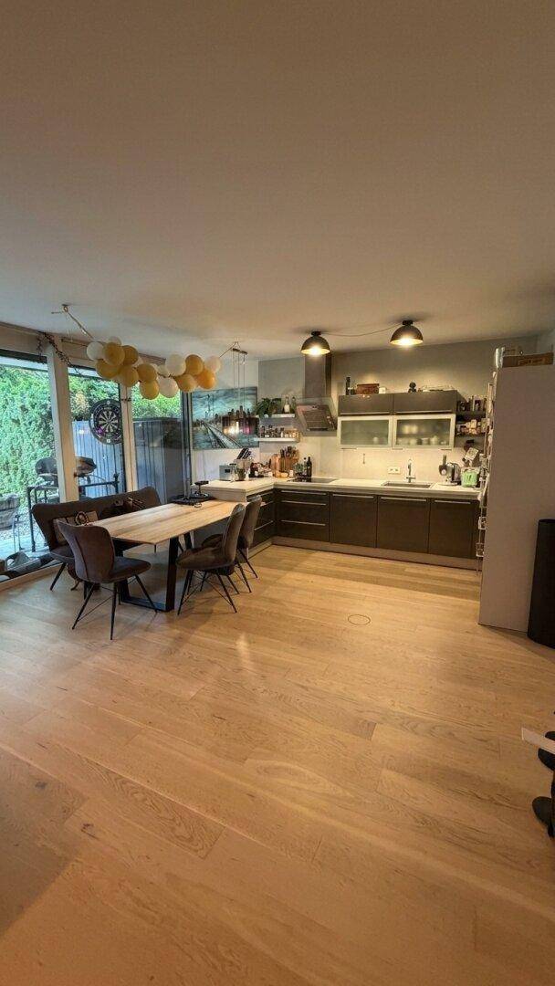 Moderner offener Wohn-Essbereich mit integrierter Küche und Holzboden.