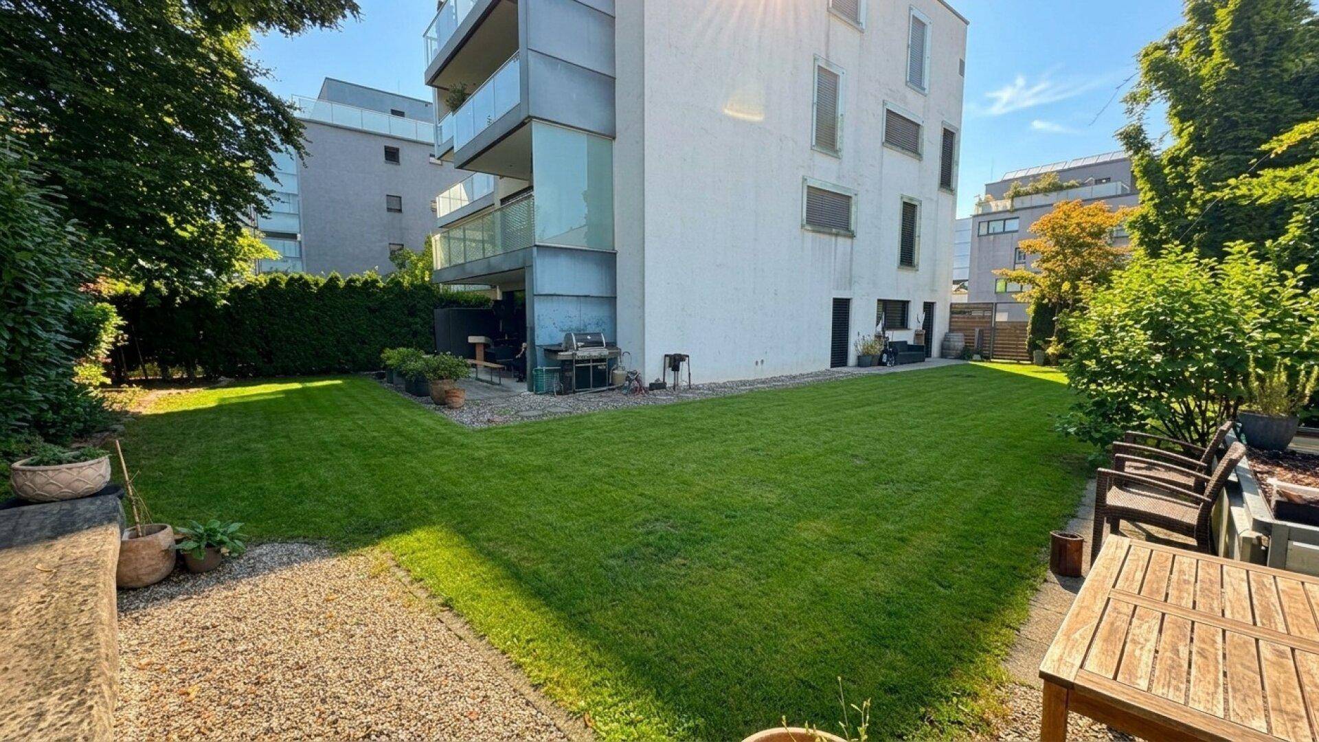 Weitläufige Rasenfläche im Gemeinschaftsgarten eines modernen Wohngebäudes mit Balkonen.